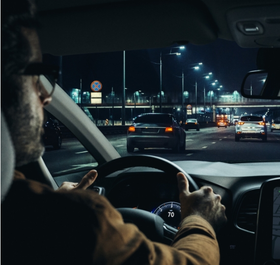 Mann mit Autofahrerbrille blickt durch die Frontscheibe seines Autos. 